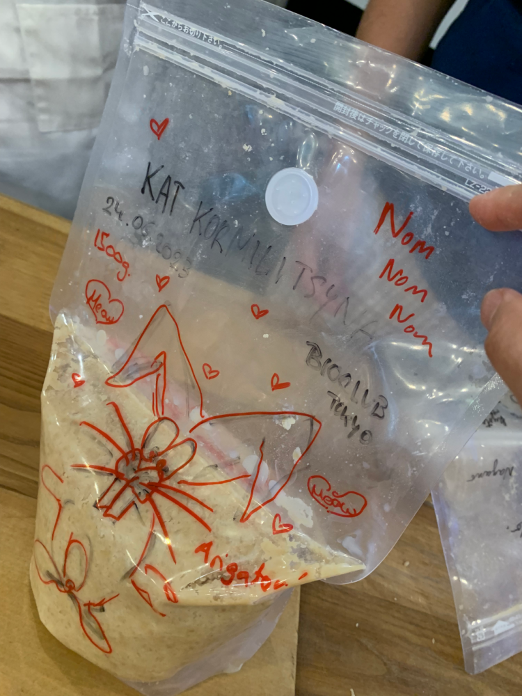 A photo of tan soybean mash in a vacuum sealed bag. The bag is decorated in black and red marker with a drawing of a stylized rabbit, several names, and the date.