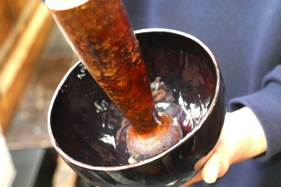 乾燥させるために漆を固めた物で器とツク棒(塗り〜乾燥のための持ち手)を接着している様子。